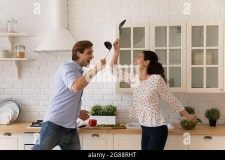 Lachende Ehegatten, die Spaß am Küchekampf in verrückter Stimmung haben Stockfoto