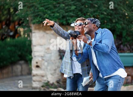 Glückliche Momente. Fröhliches Paar mit dunkler Haut, das während einer romantischen Date-Reise mit afroamerikanischen Ehegatten mittleren Alters auf der Reise fotografiere. Frau Stockfoto