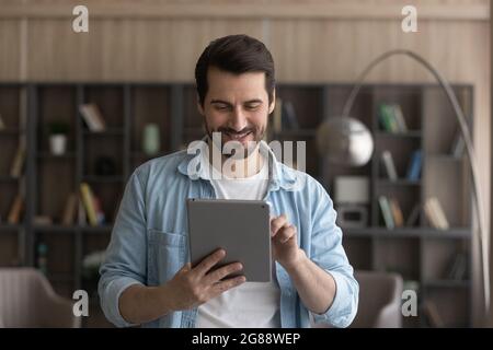 Glücklicher junger kaukasischer Mann mit digitalem Computer-Tablet. Stockfoto