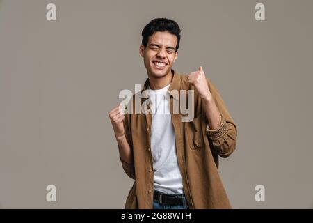 Brünette hispanischen Mann im Hemd lächelnd, während tanzen isoliert über grauen Hintergrund Stockfoto