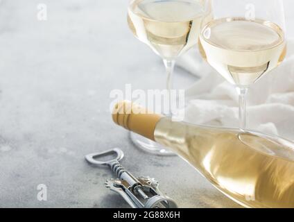 Zwei Kristallgläser und eine Flasche hausgemachten weißen Wein mit Stahlkorkenzieher auf hellem Tischhintergrund. Platz für Text Stockfoto