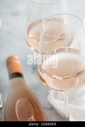 Zwei Kristallgläser und eine Flasche hausgemachten Rosé-Weins auf hellem Tischhintergrund. Draufsicht. Makro Stockfoto