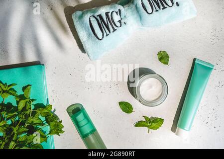 Gläser kosmetische Creme mit grünen Blättern, omg Haarband und Notizbuch minzfarben auf weiß mit Schatten, Oberkante Stockfoto