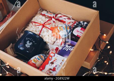 Lviv, Ukraine - 1. Dezember 2017: Hausgemachte Marmelade, Marmeladen, Tasse, kinder Pralinen in Geschenkbox in festlichen Lichtern. Stilvolle Geschenkbox für Süßigkeiten Stockfoto
