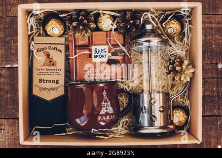Lviv, Ukraine - 1. Dezember 2017: Gerösteter Kaffee, französische Presse, Tasse und ritter Sport Schokolade auf Stroh in Geschenkbox. Stilvolle Kaffee-Geschenkbox für chris Stockfoto