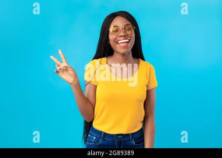 Erfolgreiche African American Lady Gestikuliert Siegeszeichen Auf Blauem Hintergrund Stockfoto