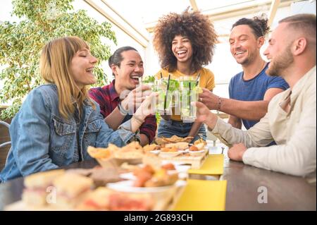 Fröhliche Gruppe von multirassischen Freunden, die Mojito-Cocktails trinken und im Restaurant der Brauerei-Bar toasten - Freundschaftskonzept mit jungen Leuten, die drun trinken Stockfoto
