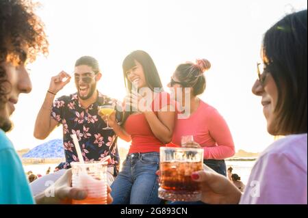 Multirassische Freunde machen verrückte Gesichter lächelnd an der Strandbar, während sie einen Cocktail trinken - Sommerfreundschaftskonzept mit jungen Menschen, die gemeinsam Spaß haben Stockfoto