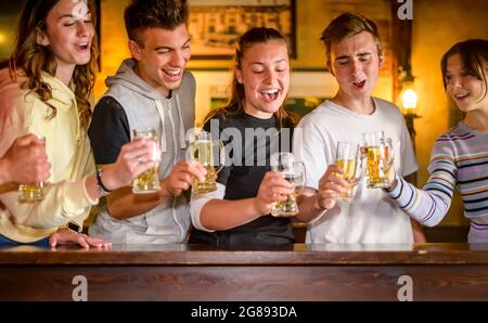 Gruppe von Millennials glückliche Freunde, die im schottischen Pub Bier trinken und toasten - Junge Teenager, die gemeinsam in einem Bar-Restaurant Spaß haben - Konzept über Stockfoto