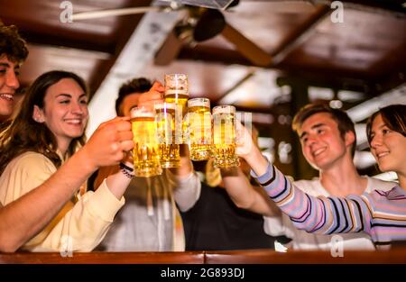 Eine Gruppe von glücklichen jungen Freunden, die im Pub Bier trinken und toasten - Konzept über Freundschaft, Leute, die gemeinsam im Restaurant Spaß haben - Schwerpunkt auf Pint gl Stockfoto