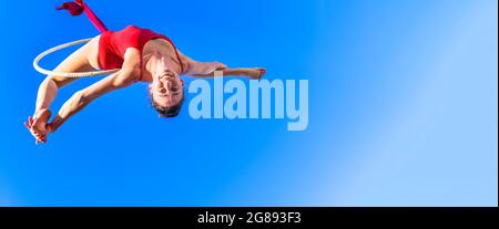 Outdoor-Aktivität der Turnerin Durchführung Training auf dem Reifen in den Himmel - Mädchen tanzen und machen akrobatische Trick in der Luft, Sport, aktiv, Stockfoto