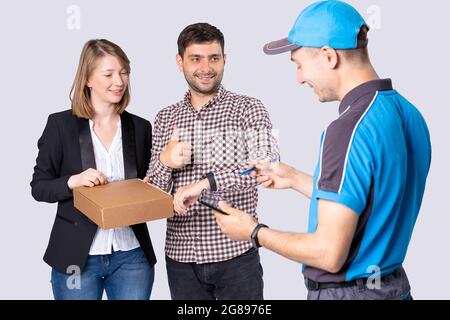 Die jungen Leute haben das Geschäftspaket rechtzeitig erhalten, so dass der Mann seinen Daumen nach oben zeigt und sie für die Lieferung unterschreiben müssen. Stockfoto