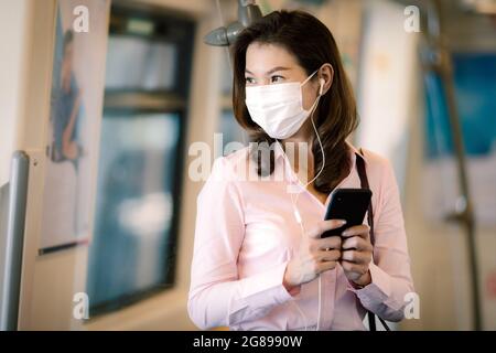 Schöne niedliche Smiley asiatische Geschäftsfrau trägt schützende chirurgische Hygienemaske auf dem Gesicht verhindern, dass Risiko von Coronavirus, covid-19 Ausbruch, mit Stockfoto