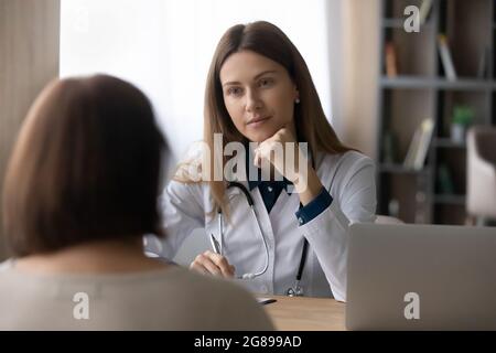 Seriöse Ärztin besucht weibliche Senioren und gibt eine Konsultation Stockfoto