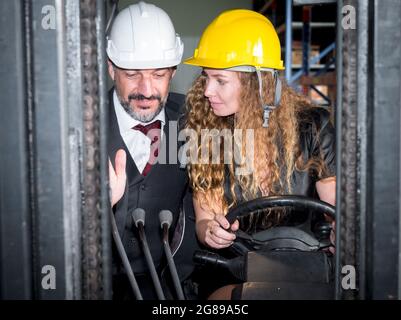 Selektiver Fokus, Lustige Zeit, EINE weibliche Lagermanagerin, die einen Gabelstapler fährt, um die Aktionäre zu bringen, um die fertigen Waren im Lager zu besichtigen. Stockfoto