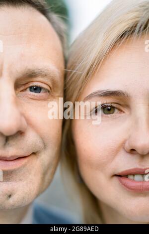 Nahaufnahme einer Hälfte der Gesichter eines gutaussehenden Mannes mittleren Alters und einer attraktiven blonden Frau, die mit einem schönen Lächeln auf die Kamera blickt Stockfoto