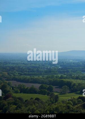 Heller, luftiger Blick über ein von Feldern und Wäldern bedecktes Tal zu einem fernen, von Dunst umhüllten und von Hügeln umrandeten Horizont. Stockfoto