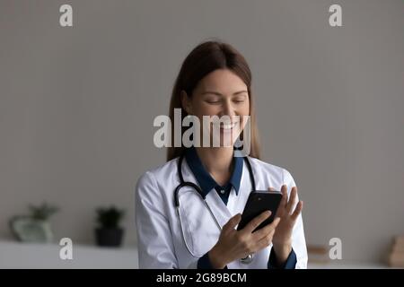 Glückliche Ärztin mit App auf dem Smartphone für die Terminvereinbarung Stockfoto