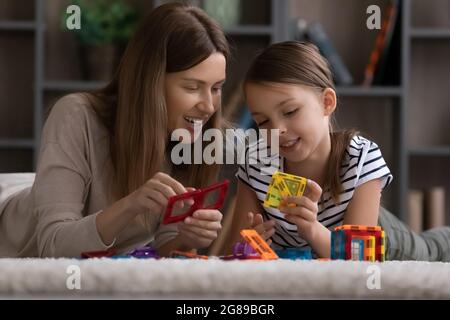 Nettes Mädchen und glückliche Mutter beschäftigt in Lernspiel zusammen Stockfoto