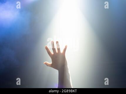 Ein Strahl von Neonlicht aus dem Pub scheint durch die Hand eines jungen Mannes mit fünf Daumen-up-Symbole helfen oder hoffen. Stockfoto