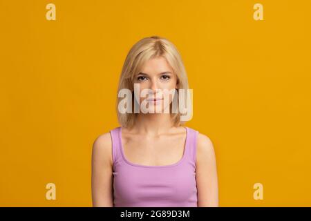 Nahaufnahme Porträt einer jungen Dame mit ernstem Ausdruck auf ihrem Gesicht posiert über gelben Studio-Hintergrund, kopieren Raum Stockfoto