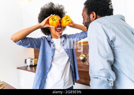 Schönes afro amerikanisches Paar, das zu Hause kocht - schönes und fröhliches schwarzes Paar, das das Abendessen zusammen in der Küche zubereitet Stockfoto