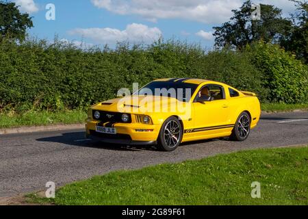 2008 gelbes Ford Mustang 2dr Fastback-Benzinfahrzeug auf dem Weg zur Capesthorne Hall Classic July Car Show, Ceshire, Großbritannien Stockfoto