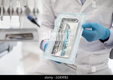 Nicht Erkennbarer Zahnarzt Arzt In Uniform Demonsting Versiegelten Sterilisationsbeutel Mit Dental Tools Stockfoto