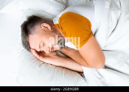 Draufsicht - ein Mann mittleren Alters schläft. Gesundes Schlaf- und Erholungskonzept. Stockfoto