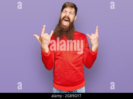 Rotschopf Mann mit langen Bart tragen lässige Kleidung schreiend mit verrückten Ausdruck Rock-Symbol mit Händen nach oben. Musik-Star. Heavy-Konzept. Stockfoto