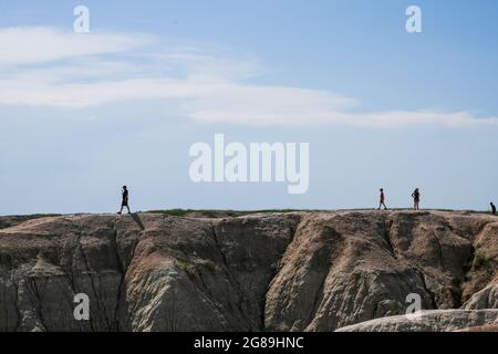 Im Badlands National Park, South Dakota, USA, wandern Touristen mit Silhouetten entlang einer Gratlinie. Stockfoto