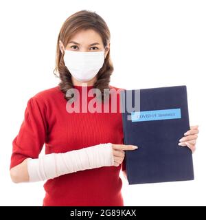 Schöne asiatische Frau mit gebrochenem Arm und Verband tragen chirurgische schützende Hygienemaske stehend isoliert auf weißem Hintergrund. Ein Leben lang halten Stockfoto
