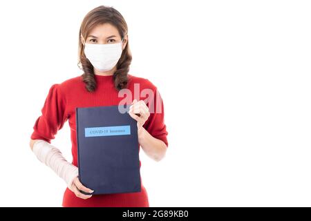 Schöne asiatische Frau mit gebrochenem Arm und Verband tragen chirurgische schützende Hygienemaske stehend isoliert auf weißem Hintergrund. Ein Leben lang halten Stockfoto