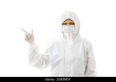 Frau in sterilisiertem Laborkittel und Sicherheitsbrille, die auf weißem Hintergrund isoliert und mit dem Finger auf den Platz zeigt und auf die Kamera schaut. Idee Stockfoto