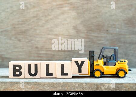 Spielzeug Gabelstapler halten Buchstaben Block y Wort Bully auf Holz Hintergrund zu vervollständigen Stockfoto