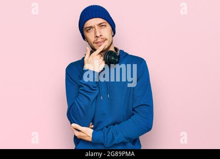 Hispanic junger Mann trägt Sweatshirt und Wollmütze ernstes Gesicht denken über Frage mit Hand auf Kinn, nachdenklich über verwirrende Idee Stockfoto