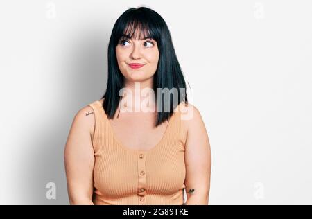 Junge hispanische Plus-Größe Frau in legerer Kleidung lächelnd zur Seite schauen und weg denken starren. Stockfoto