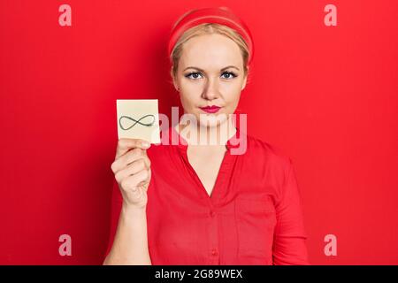 Junge blonde Frau hält unendliche Symbol Erinnerung Denken Haltung und nüchternen Ausdruck selbstbewusst aussehen Stockfoto