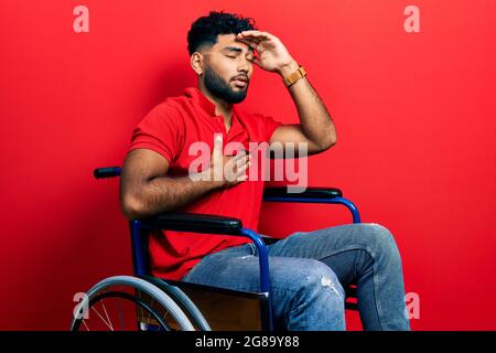 Arabischer Mann mit Bart, der auf dem Rollstuhl sitzt und die Stirn wegen Krankheit und Fieber, Grippe und Erkältung berührt, viruskrank Stockfoto