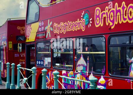 Farbenfrohe Doppeldecker-Reisebusse warten an den Bushaltestellen, um Passagiere für ihre Fahrten entlang der Küste von Brighton nach Eastbourne abzuholen Stockfoto