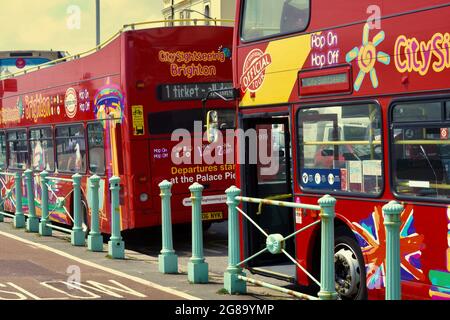 Farbenfrohe Doppeldecker-Reisebusse warten an den Bushaltestellen, um Passagiere für ihre Fahrten entlang der Küste von Brighton nach Eastbourne abzuholen Stockfoto