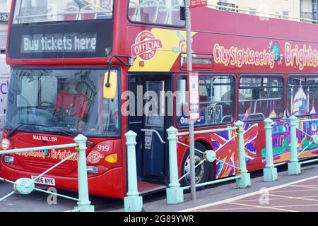 Farbenfrohe Doppeldecker-Reisebusse warten an den Bushaltestellen, um Passagiere für ihre Fahrten entlang der Küste von Brighton nach Eastbourne abzuholen Stockfoto