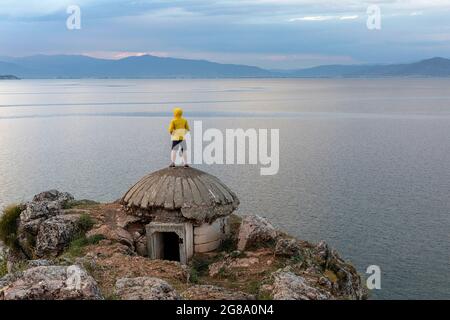 Junge, der auf einem alten Bunker am Ohridsee in der Nähe von Lin, Region Korca, Albanien, steht Stockfoto