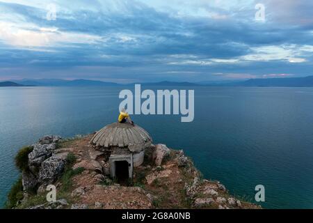 Junge sitzt auf dem Dach eines alten Bunkers am Ohridsee, in der Nähe von Lin, Region Korca, Albanien Stockfoto