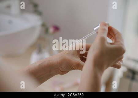 Frau feuchtigkeitsspendende Haut Hand mit Öl Produkt mit Pipette. Natürliches organisches Kosmetik- und Hautpflegekonzept Stockfoto
