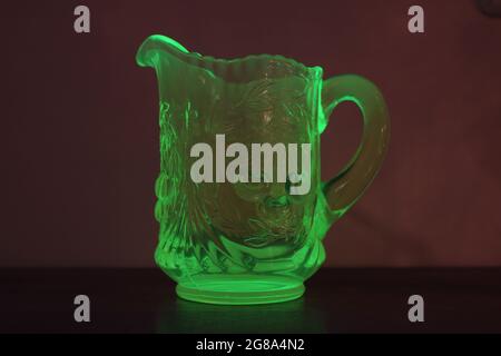 Ein Vintage-Uran-Glas-Creamer, der unter einem schwarzen Licht leuchtet Stockfoto