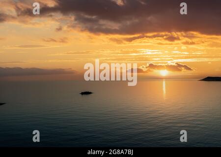 Sonnenuntergang über der ruhigen Ägäis. Kykladen-Inseln. Griechenland. Dramatischer Himmel und Wolken gelb orange Farben, Luftdrohne Ansicht. Stockfoto