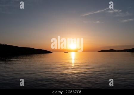 Sonnenaufgang über dem ruhigen Ägäischen Meer. Kykladen-Inseln. Griechenland. Dramatischer Himmel gelb orange Farben, Luftdrohne Ansicht. Sonne aufgehende goldene Reflexe auf Welligkeit Stockfoto