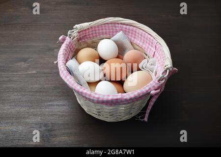 Eier im Korbkorb auf Holztisch. Stockfoto