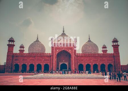 Badshahi Masjid, bekannt als Kings Mosque in lahore, am Abend mit Kindern, die im Garten der Moschee spielen und mit der Stadt lahore im Hintergrund Stockfoto